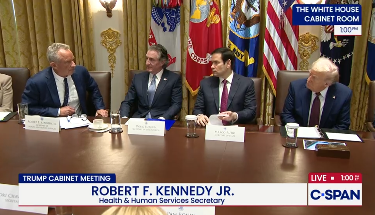Robert F. Kennedy Jr. speaks across a table to President Trump during a cabinet meeting, with Doug Burgum and Marco Rubio looking on