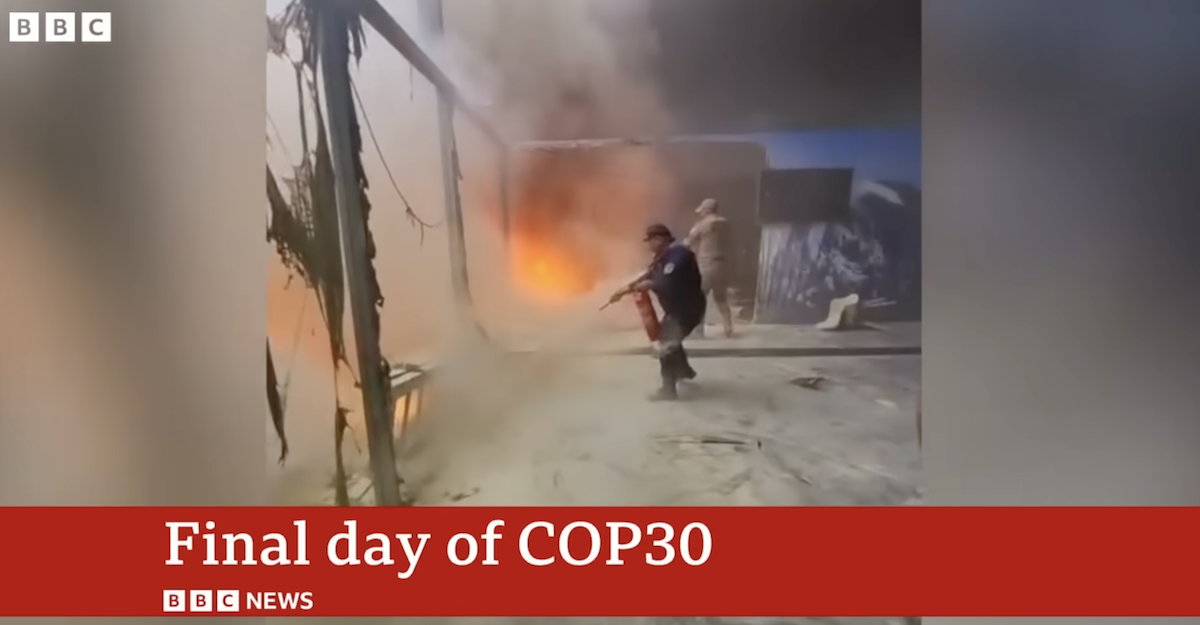 A man wields a fire extinguisher as flames burn inside the COP30 pavillion