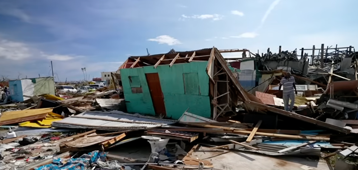 Structures are flattened and in pieces as a man walks through the rubble